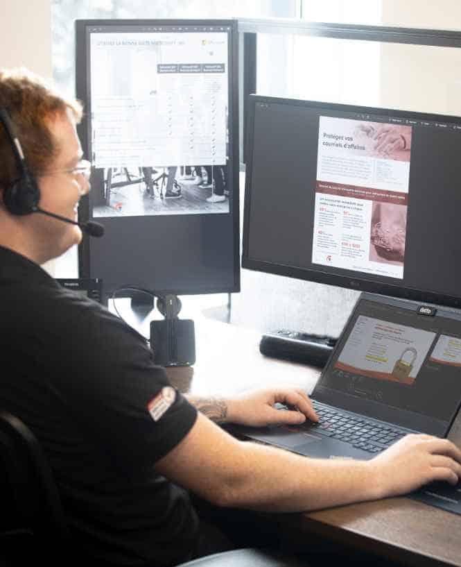 Un technicien souriant regarde ses écrans d'ordinateur